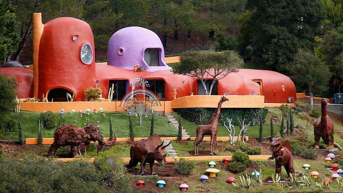 Colorful bizarre building with animal sculptures in a whimsical garden, showcasing unique architectural design and creativity.