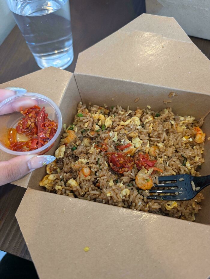 Cardboard box of fried rice with chili; extra chili served on the side.