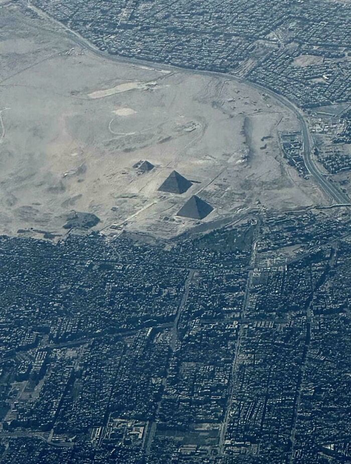 Aerial view of urban area near ancient pyramids, illustrating global urban hell contrasts.