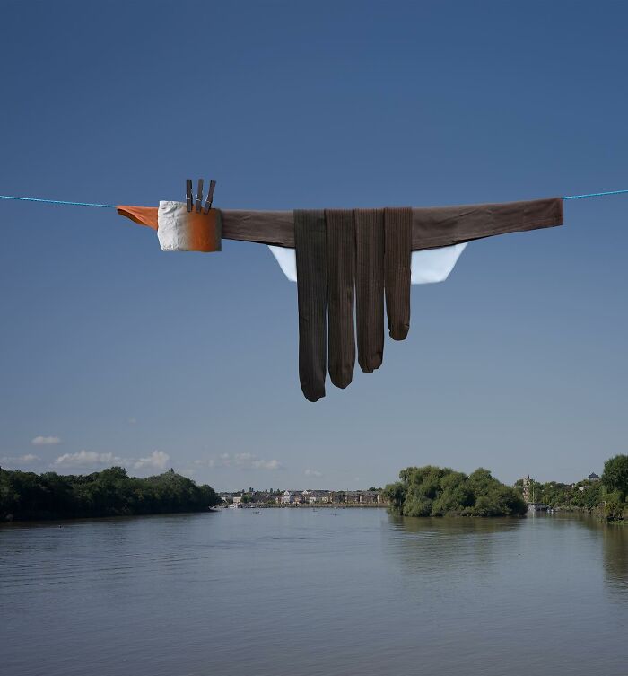 Playful animal made from laundry hanging on a line with picturesque river landscape and blue sky background.