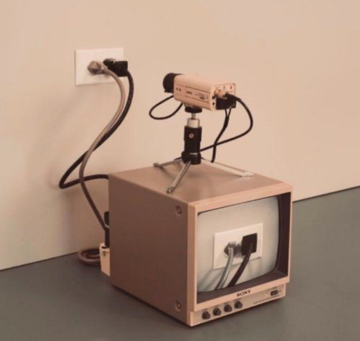 A Sony camera filming a power outlet, displayed on a monitor, creating a curious loop.