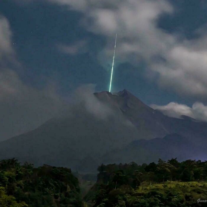 Rayo de luz en el cielo nocturno sobre un volcán, demostrando la sorpresa de la naturaleza.
