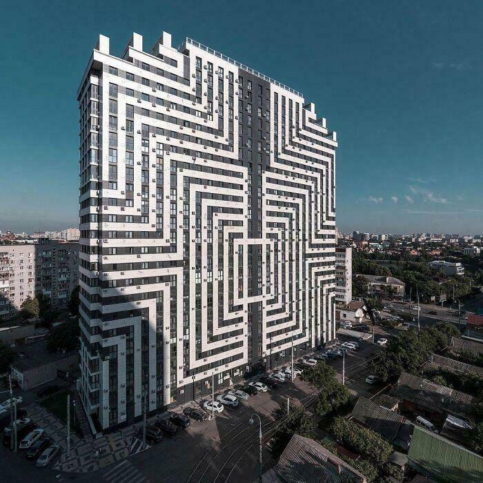 Modern bizarre building with unique black and white geometric patterns creating optical illusions in urban area.