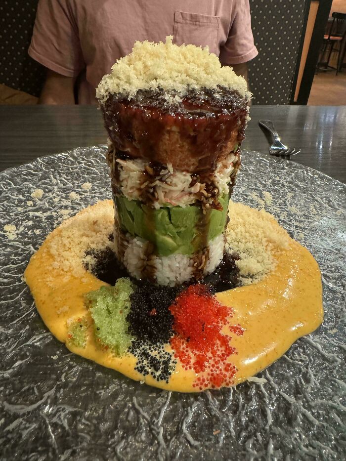 Tall layered sushi dish with various sauces and toppings, showcasing one of the most ridiculous ways food had been served in restaurants.