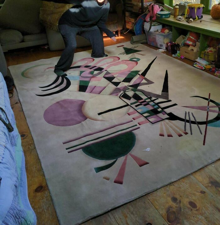 Person admiring a geometric patterned rug they found while thrifting, surrounded by a cozy room setting.
