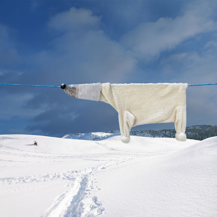 Playful animal made from laundry hanging on a line with snowy picturesque landscape under a moody sky.