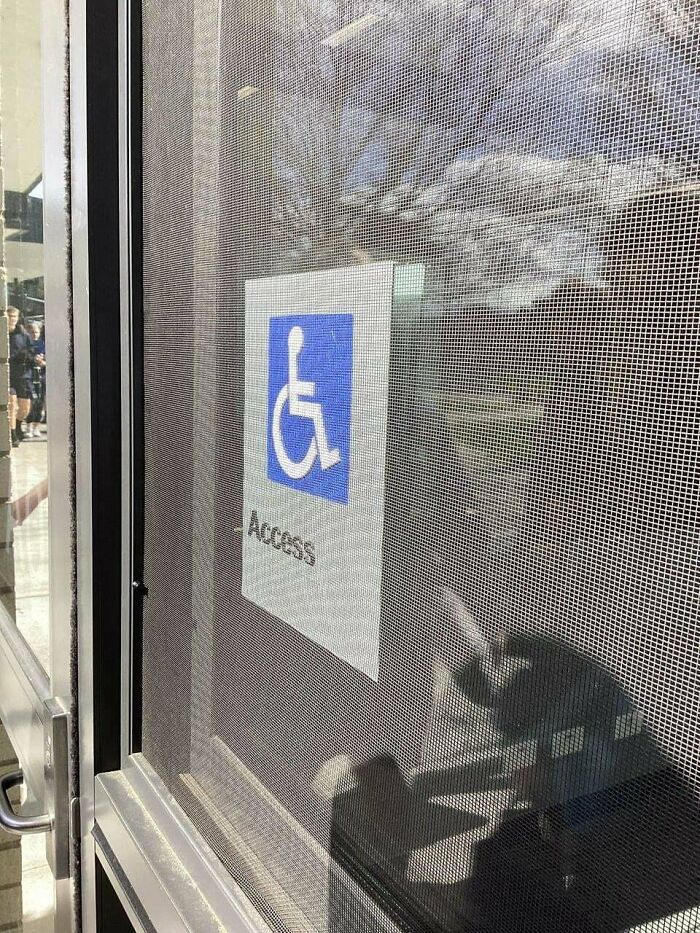 Handicap access sign posted on a door covered by a metal mesh screen, showing a perfectly preventable fail.