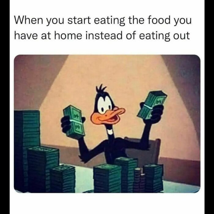 Relatable meme showing cartoon duck happily holding stacks of money with caption about eating food at home.