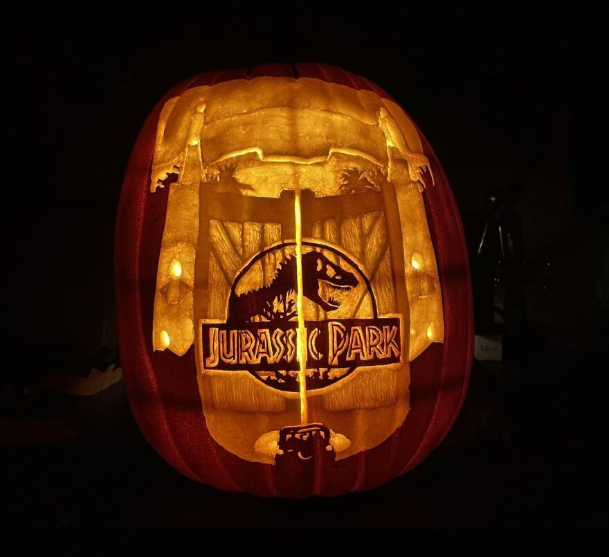 Intricately carved Jurassic Park pumpkin glowing in the dark, showcasing spooky and quirky pumpkin carvings artistry.