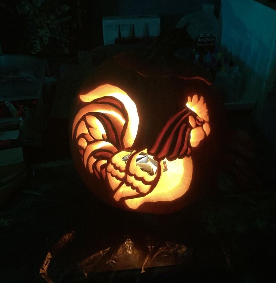 Glowing pumpkin carving of a detailed rooster, showcasing quirky and charming pumpkin carvings creativity at night.