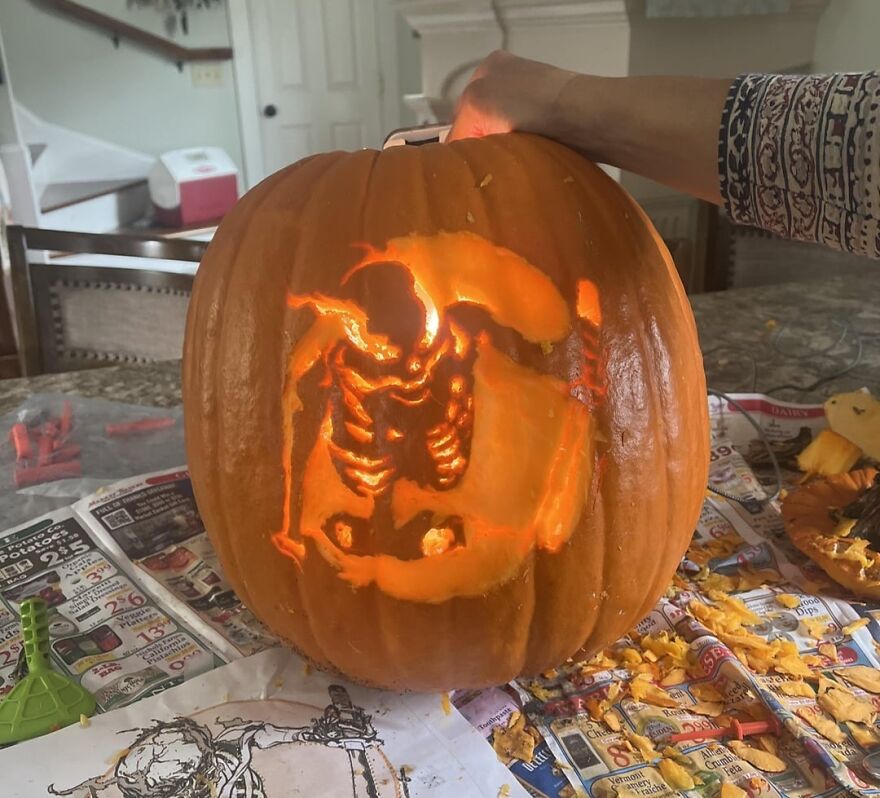 Carved pumpkin featuring a detailed, spooky skeleton design glowing from inside, showcasing quirky pumpkin carvings.