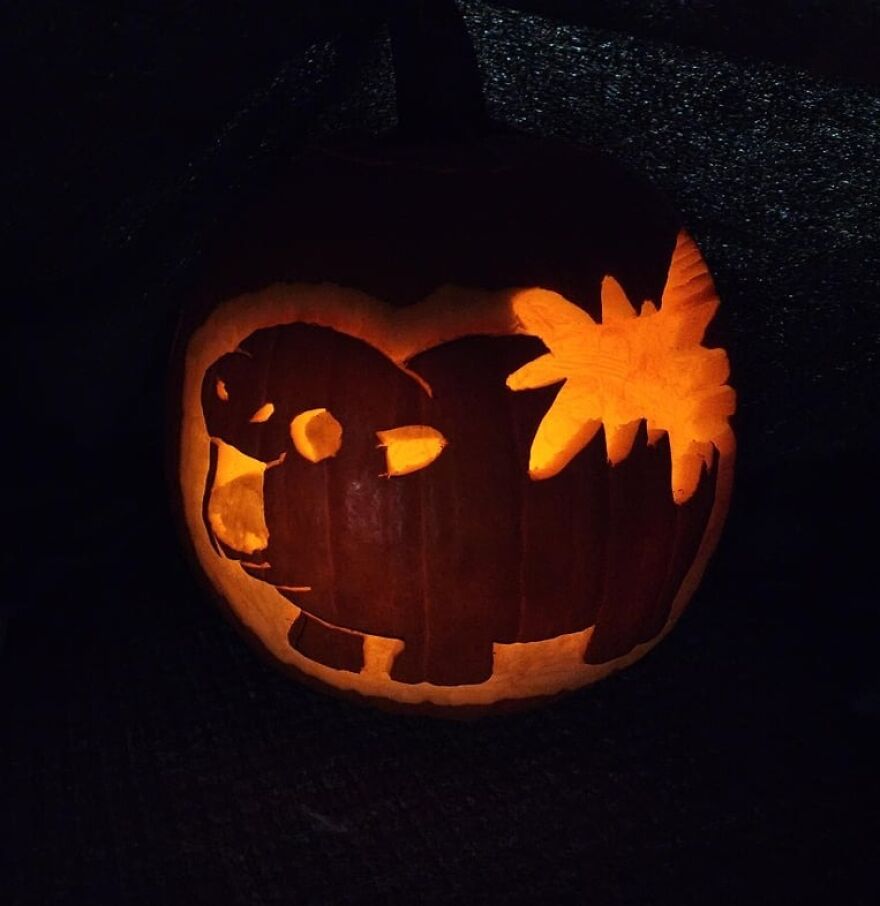 Pumpkin carving of a monkey holding a palm tree, glowing warmly in the dark, showcasing quirky pumpkin carvings.