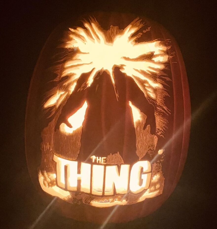 Pumpkin carving glowing in the dark featuring a detailed and spooky design inspired by The Thing movie poster.