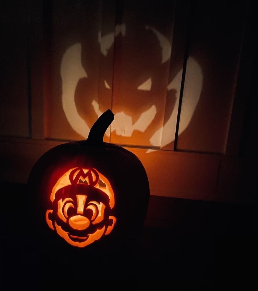 Pumpkin carving of a cartoon character with glowing light casting a spooky and quirky shadow on a wall behind it.