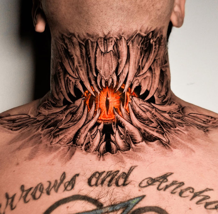  An intense neck tattoo featuring an open, jagged mouth-like design with an eerie, glowing orange eye at its center. Tattoo ideas for men who want a striking, dark, and fantasy-inspired look.