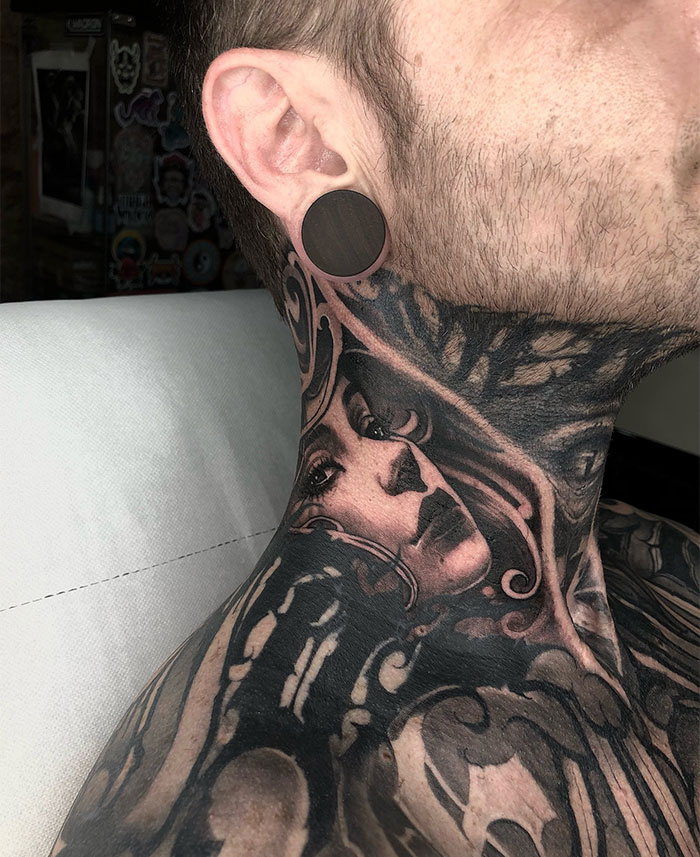  A detailed black and grey neck tattoo featuring a woman's face intertwined with artistic patterns. Tattoo ideas for men seeking intricate and expressive designs.
