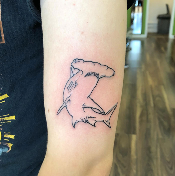  Minimalist line tattoo of a hammerhead shark on the upper arm. Tattoo ideas for men seeking a simple ocean-themed design with a bold yet clean look.
