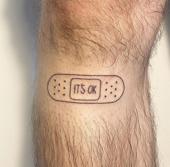  A minimalist tattoo on the wrist depicting a small bandage with the text "IT'S OK" in the center. A simple and meaningful tattoo idea for men symbolizing resilience and reassurance.
