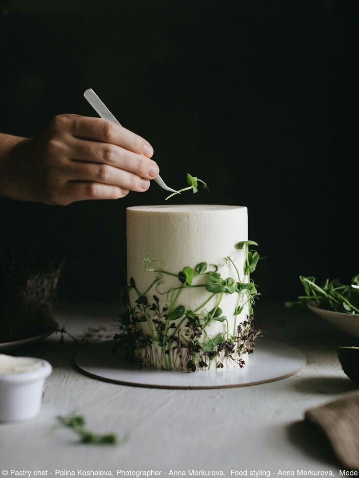 Hand decorating a frosted cake with herbs, celebrating National Cake Day with Tiptree Cake Awards.