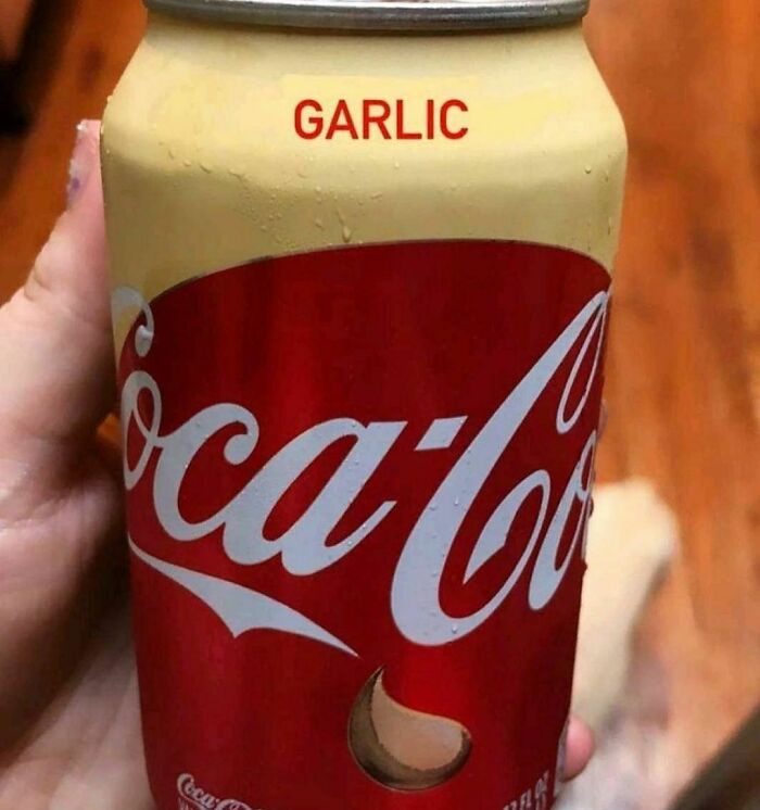 Hand holding a Coca-Cola can with a garlic flavor label, showing a dark hilarious twist in bizarre reality.