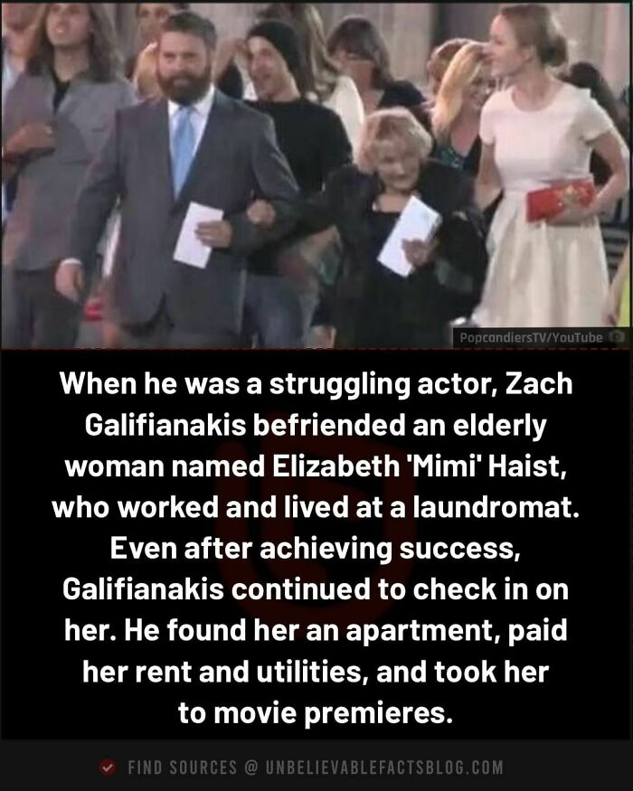 Man in a suit walking with an elderly woman at a premiere, capturing an interesting moment of friendship.