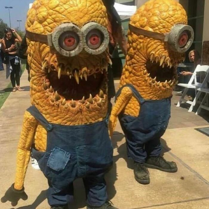 Two bizarre, darkly twisted characters resembling distorted minions with sharp teeth and textured yellow skin stand outdoors.