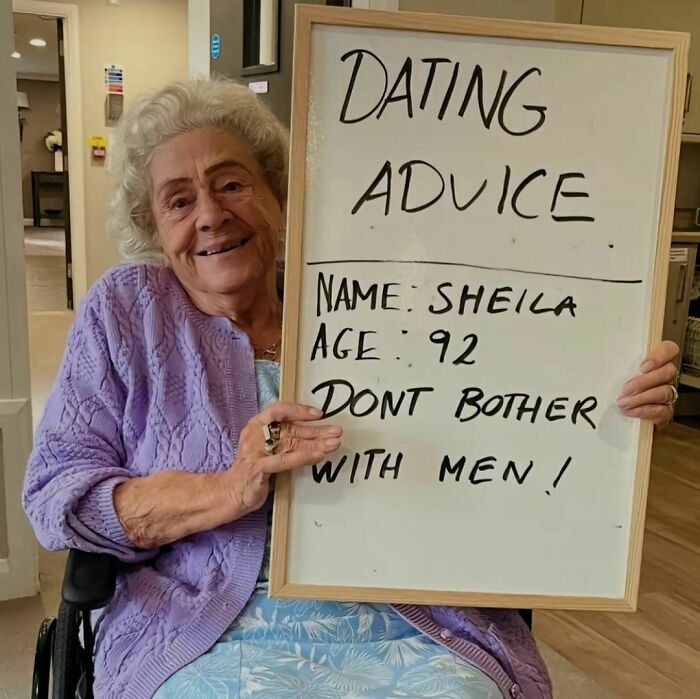 Elderly woman smiling and holding a sign with dating advice in a lighthearted random photo to brighten your day.