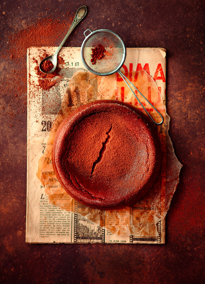 Rich chocolate cake on vintage paper, dusted with cocoa, celebrating cakes worldwide.