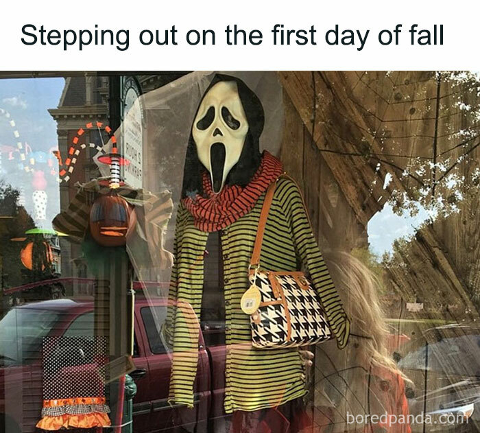 Meme of a mannequin in a shop window with a spooky mask and striped outfit, embracing cozy fall vibes.