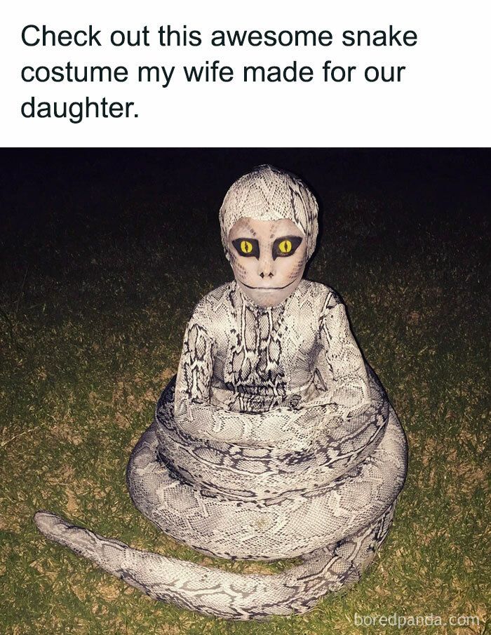 Child in a snake costume sitting on grass, showcasing a creative Halloween look.