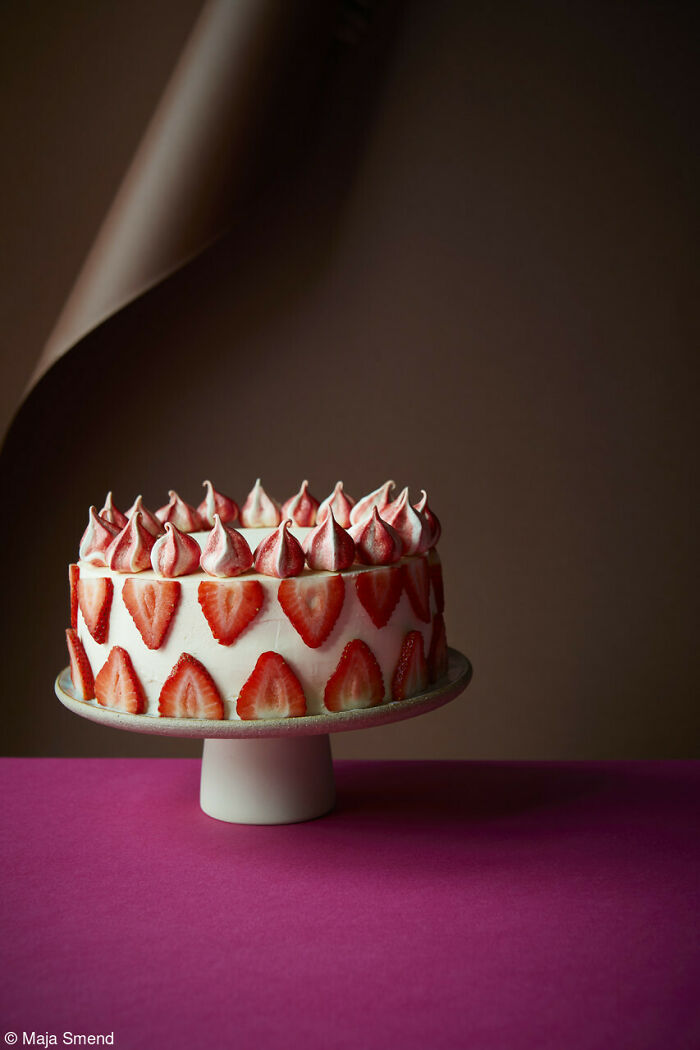 Strawberry cake with meringue peaks on a pedestal, celebrating National Cake Day.