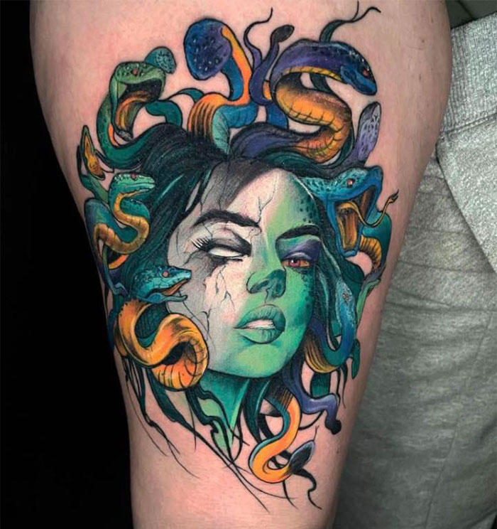 Colorful Medusa tattoo with greenish skin, c*****d markings, and vibrant snakes in hair, symbolizing beauty and defiance.