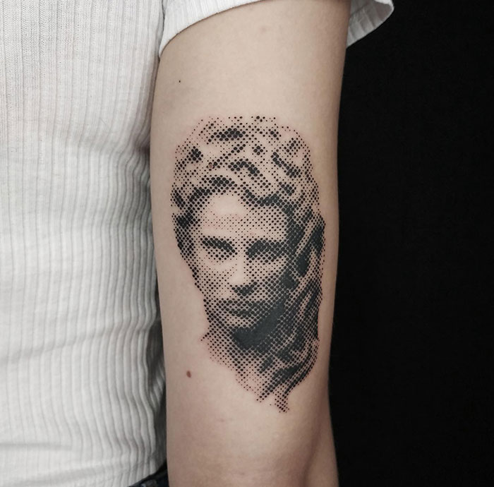 Minimalist Medusa tattoo on arm, dotwork technique, showcasing beauty, power, and defiance.