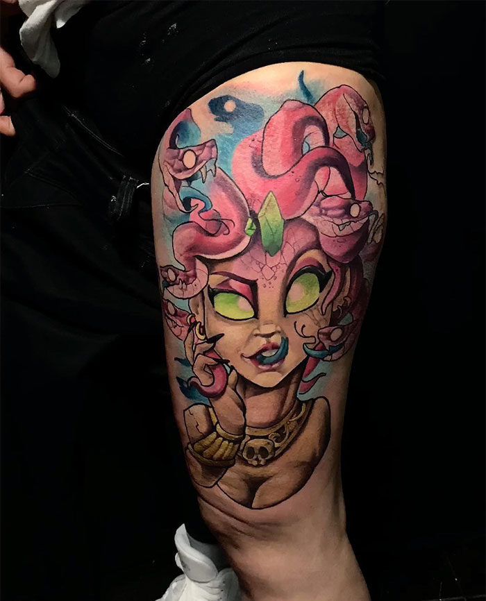 Playful Medusa tattoo on thigh with glowing green eyes, pink snakes, and a skull necklace, symbolizing beauty and power.