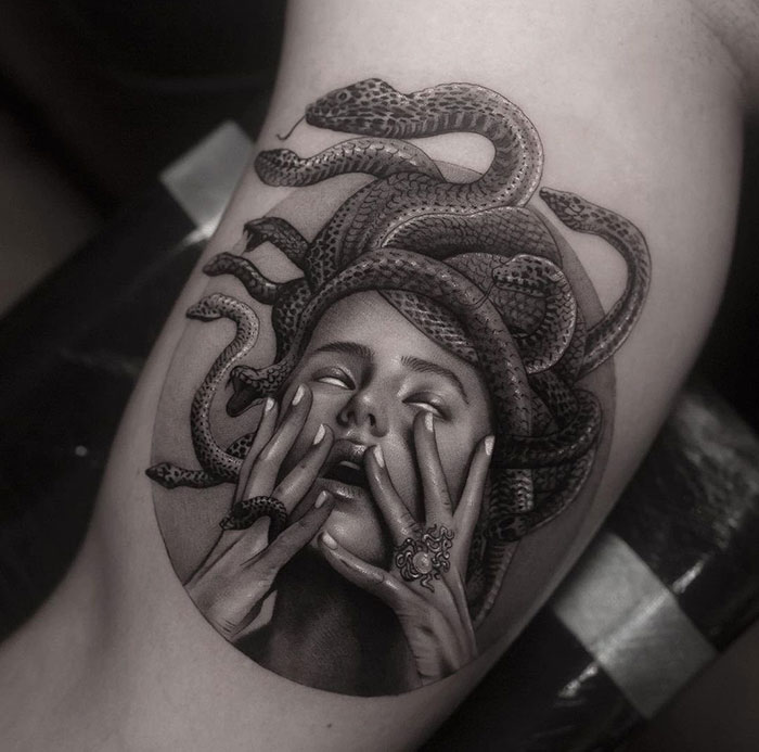 Realistic black and grey Medusa tattoo with snakes around her head, symbolizing beauty, power, and defiance.