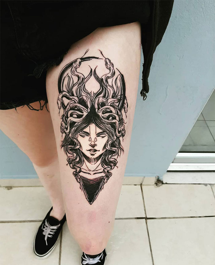 Black ink Medusa tattoo on thigh, depicting a woman's face with snakes, symbolizing beauty, power, and defiance.