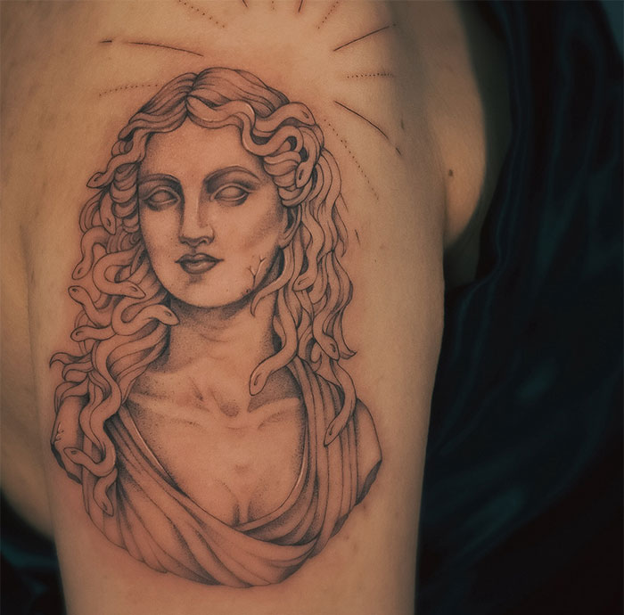 Medusa tattoo with sculptural shading, fine lines, and snakes in hair, symbolizing beauty, power, and defiance.