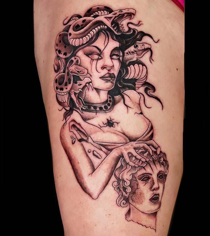 Medusa tattoo with snakes in hair, holding a c*****d stone bust, symbolizing beauty, power, and defiance.
