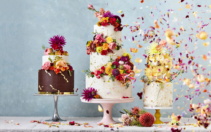 Three decorative cakes adorned with vibrant flowers for Tiptree Cake Awards, celebrating National Cake Day.