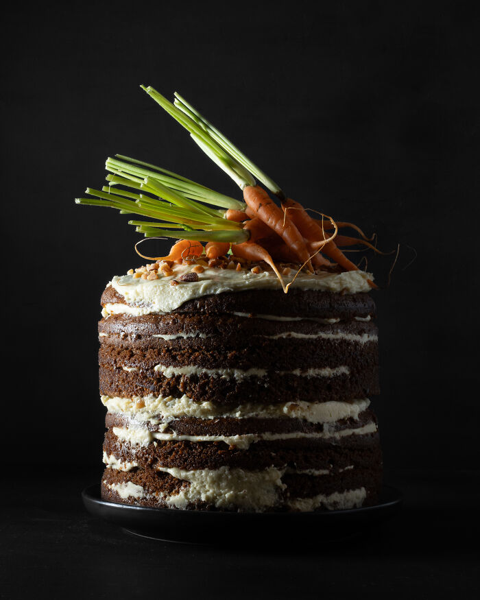 Layered carrot cake with cream cheese frosting and fresh carrots on top, celebrating National Cake Day with Tiptree Cake Awards.
