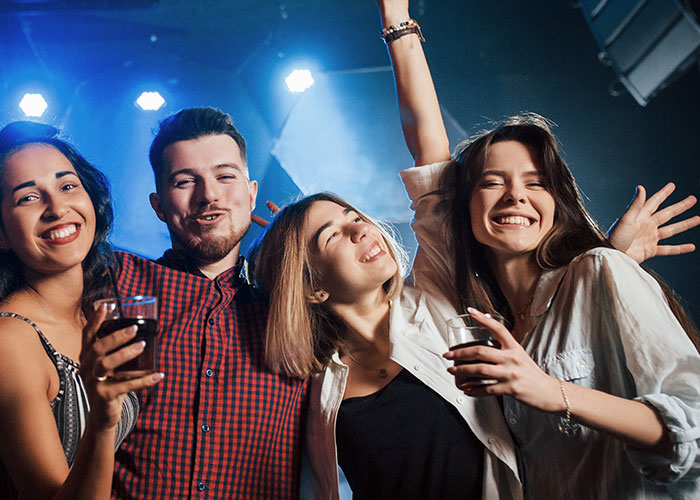 Group of friends celebrating at a party with drinks, smiling and posing together. Group of friends celebrating at a party with drinks, smiling and posing together.