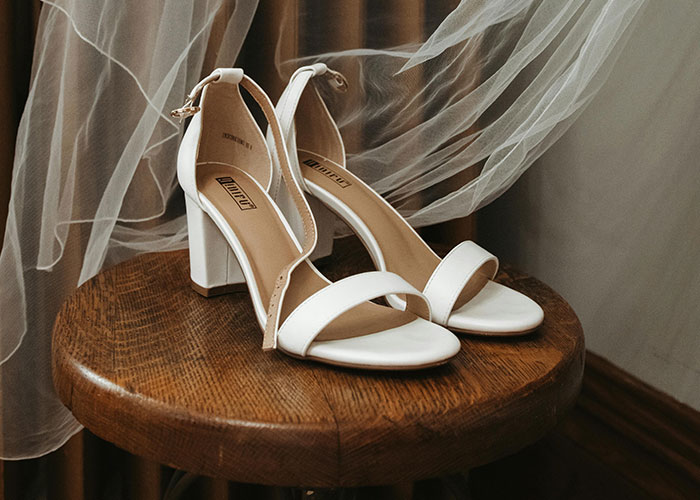 White high heels on a wooden stool with a veil, symbolizing a pre-wedding setting. White high heels on a wooden stool with a veil, symbolizing a pre-wedding setting.