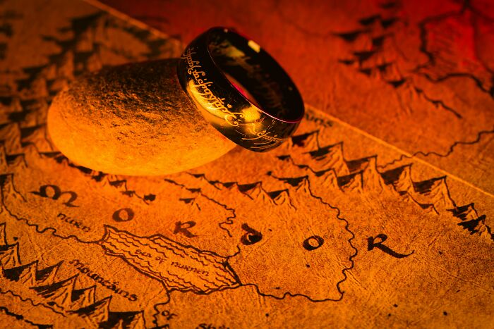 Gold ring with mysterious inscriptions resting on a stone over a detailed map, symbolizing mind-blowing coincidences.