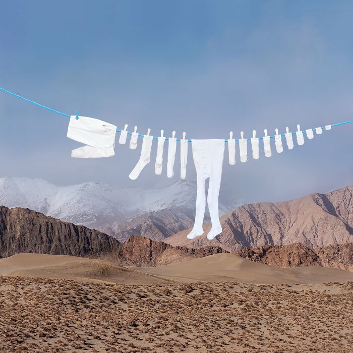 Playful animals made from laundry hanging on a clothesline against a picturesque mountain landscape.