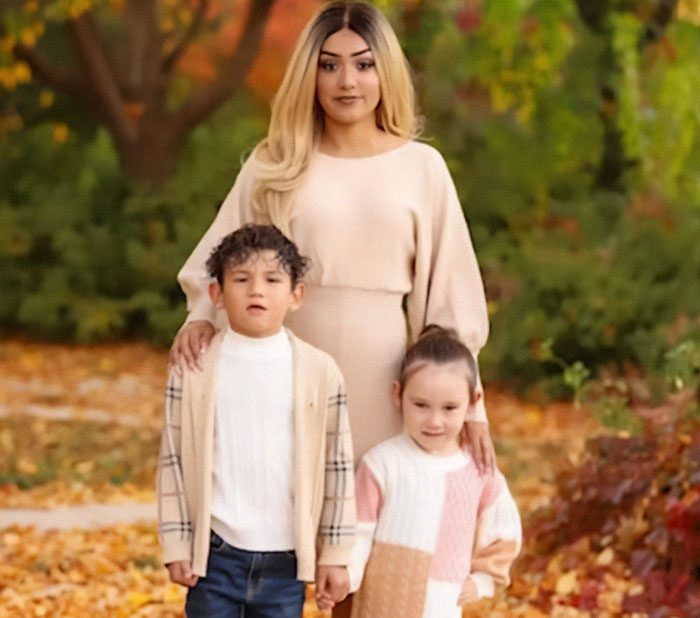 A single mom stands with her two young children in an autumn park, colorful leaves surrounding them. A single mom stands with her two young children in an autumn park, colorful leaves surrounding them.