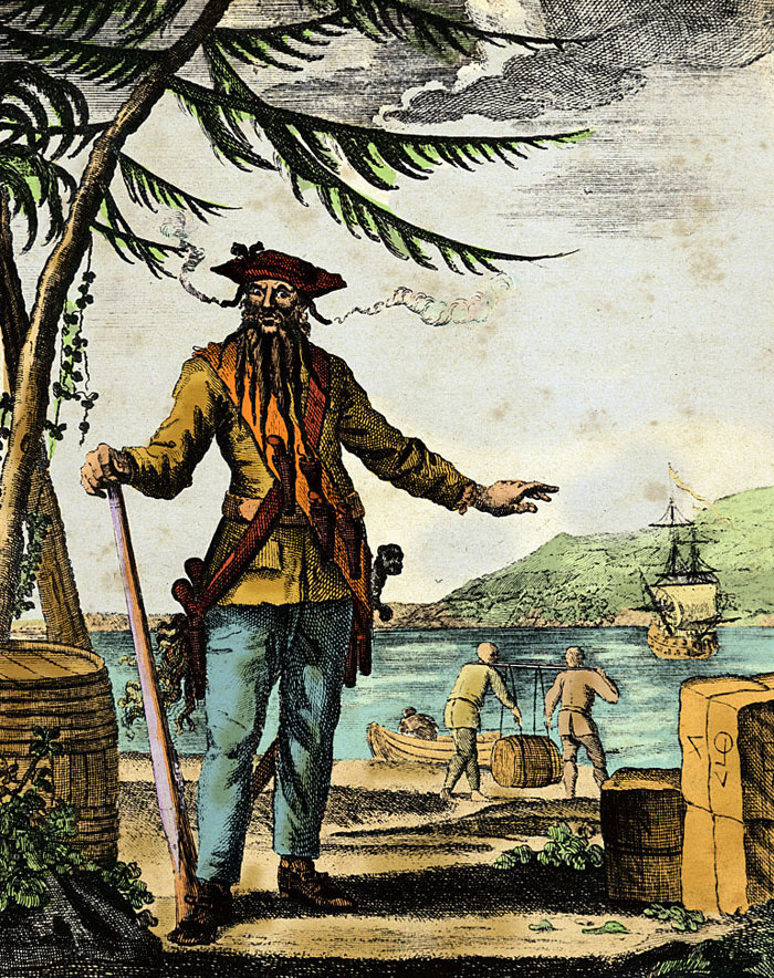  Illustration of the famous pirate Blackbeard with a long beard and smoking guns in his hat, standing on a beach with ships and crew in the background.