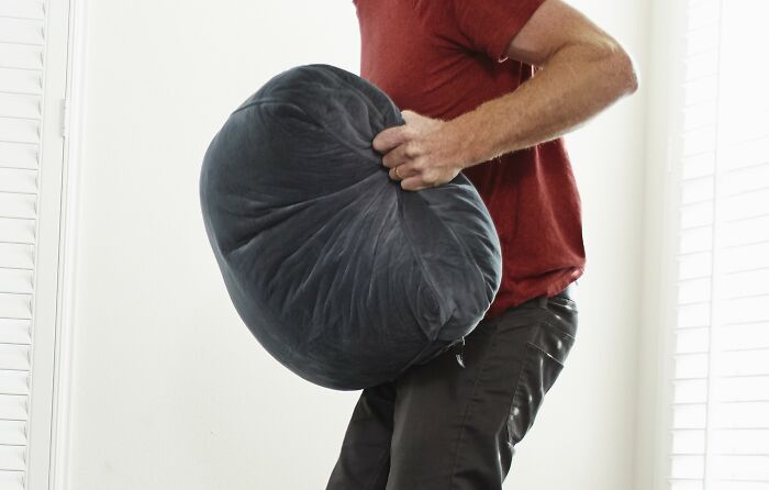 Man in a red shirt holding a large pillow, symbolizing avoiding toxic relationships and red flags.