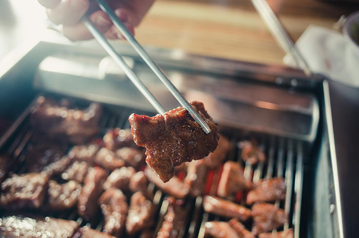 Grilled meat being picked up with chopsticks, symbolizing dining out and tipping practices. Grilled meat being picked up with chopsticks, symbolizing dining out and tipping practices.