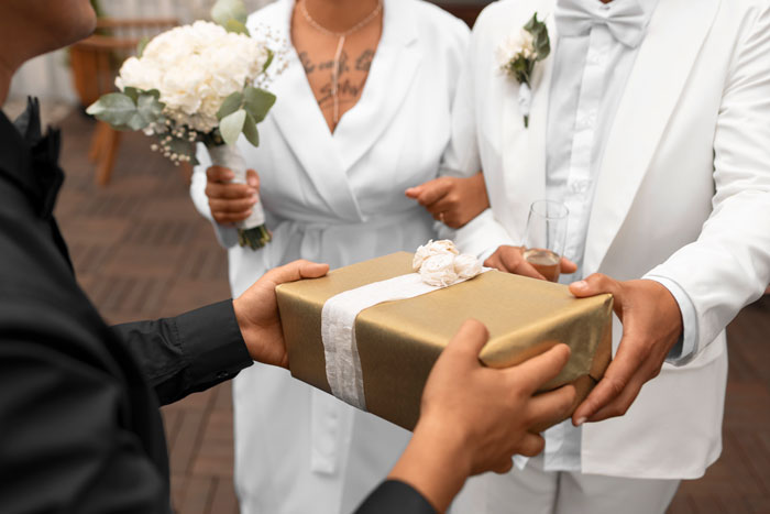 Groom-to-be receiving wedding gift from woman in white dress holding bouquet. Groom-to-be receiving wedding gift from woman in white dress holding bouquet.