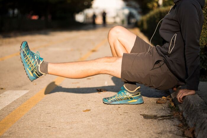 Person in sportswear stretching leg while sitting on roadside, illustrating mind-blowing coincidences in everyday moments.